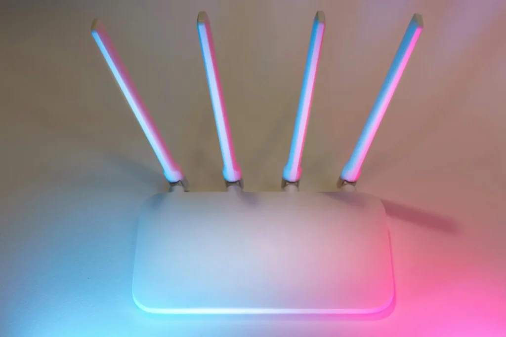 Router WiFi putih dengan empat antena dan lampu biru sebagai ilustrasi cara mengganti sandi WiFi di rumah